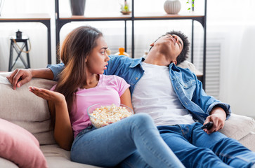 Bored guy sleeping next to girlfriend while watching movie together