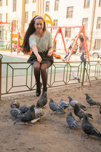 Young Woman Feeding Pigeons In The City Park
