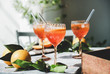 Aperol Spritz aperitif alcohol cocktail in glasses with fresh oranges and ice on grey marble board, selective focus, close-up. Summer refreshing drink concept