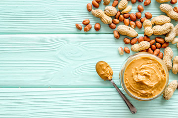 Wall Mural - Make peanut butter with paste in glass bowl on mint green wooden background top view copyspace