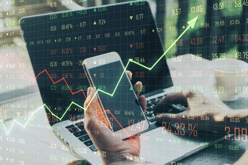 Poster - trading concept with man holding cell phone and laptop and business chart.