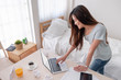© weedezign - Asian female freelancer reading report on laptop and smile with good result on table in bedroom at home.Work at home concept.work from home.relax lifestyle