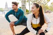 Photo Of Cheerful Man And Woman Doing Exercises And While Working Out In City Boulevard