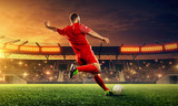 Fototapeta Sport - Soccer player kicks a ball. Night illuminated soccer stadium with dramatic sky