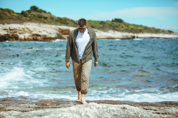 Wall Mural - man walking by rocky beach in windy day summer vacation. enjoy sea view