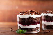 Layered Trifle Dessert With Chocolate Sponge Cake, Whipped Cream And Fruit Jelly In Serving Glasses.