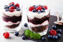 Layered Trifle Dessert With Chocolate Sponge Cake, Whipped Cream, Berries And Fruit Jelly In Serving Glasses.
