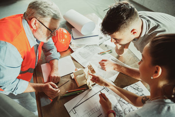 foreman or achitect engineer shows future house, office or store design plans and model to a young c