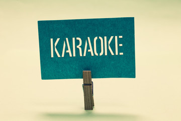 Wall Mural - Handwriting text Karaoke. Concept meaning Entertainment singing along instrumental music played by a machine Clothespin holding turquoise paper important communicate message ideas