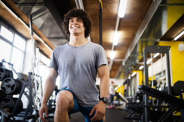 Young fit handsome man doing exercises in gym