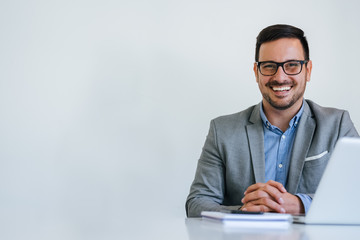 Portrait of young smiling cheerful businessman in office looking at camera copy space