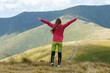 © Андрей Репетий - Happy traveling girl raising her hands while standing on the top of a hill.