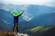 © Андрей Репетий - Woman hiker standing on the top of mountain with a raised hands