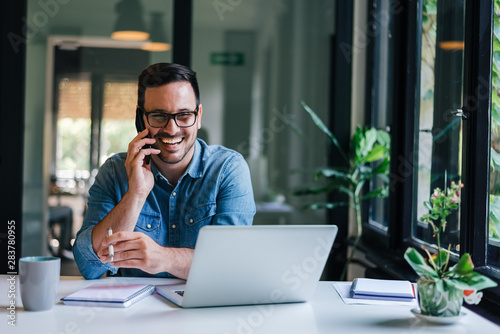Fotografía Portrait of young smiling cheerful entrepreneur in casual office making phone ca