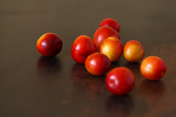 Plum fruit red yellow scattered on wooden old scratched brown tabletop.