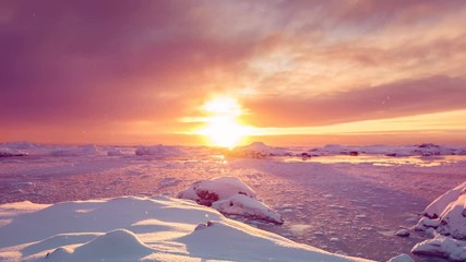 Wall Mural - antarctica sunrise behind glaciers silhouettes reflecting on frozen water under orange sky. eploring