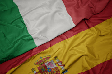 waving colorful flag of spain and national flag of italy.