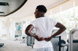 © twinsterphoto - Back view of fit African American man suffering from backache during workout in gym. Sportive man touching painful lower back