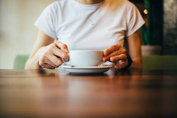 Wall Mural - Female's hands holding cup of cappuccino