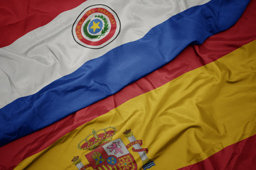 waving colorful flag of spain and national flag of paraguay.