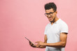 © denis_vermenko - Laughing Young African American Male Holding a Touch Pad Tablet PC  Isolated against pink Background