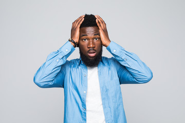 Portrait unhappy upset guy, sad young african man bothered by mistakes hands on head eyes closed isolated on grey wall background. Negative emotion face expression