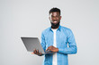 © F8  \ Suport Ukraine - Young smiling african man standing and using laptop isolated over gray background