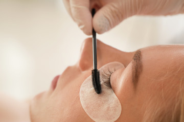 Young woman undergoing procedure of eyelashes lamination in beauty salon, closeup