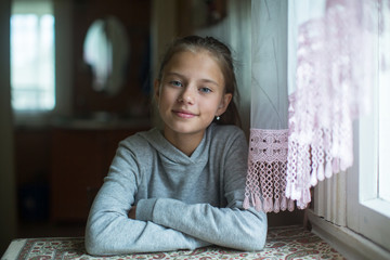 Wall Mural - Portrait of a teenage cute girl sitting at the table.