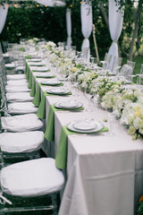 Wall Mural - wedding reception table setting, fine china plates, green napkin hanging off table, silverware, wine glasses, and flower arrangments