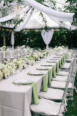 Wall Mural - Outdoor summer wedding tent decorated with hanging fabric, greenery, and crystal chandeliers, wedding reception tables, green accent color