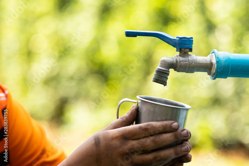 Cuadros en Lienzo Water from tab pouring in hand on nature background, Concept for save water,cons