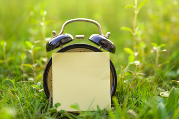 Wall Mural - analog clock with blank sticky note on nature background .selective focus