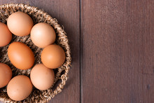 Top View Of Organic Raw Chicken Eggs In Bamboo Basket With Copy Space On Brown Wooden Floor Background