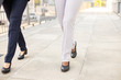 © Mangostar - Female legs walking on pavement. Cropped shot of two businesswoman strolling on street. Walking concept