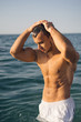 Young sporty muscular man on the beach during sunset