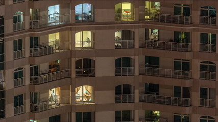 Wall Mural - Windows of the multi-storey building with lighting inside and moving people in apartments timelapse.