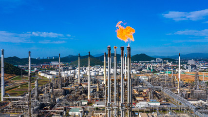 Oil​ refinery​ and​ petrochemical​ plant industrial working with fire and blue sky background, Aerial view oil and gas refinery at day.