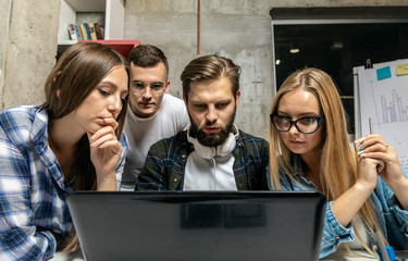 Young creative office mates having a brainstorm by a laptop