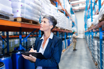 Wall Mural - Female manager checking stocks on clipboard in warehouse