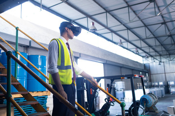 Wall Mural - Male supervisor using virtual reality headset in warehouse