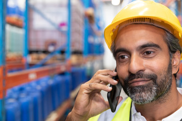 Wall Mural - Male worker talking on mobile phone in warehouse