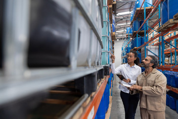 Wall Mural - Female manger and male staff interacting with each other while checking stocks