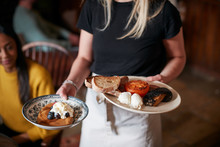 Close Up Of Waitress Working In Traditional English Pub Serving Breakfast To Guests