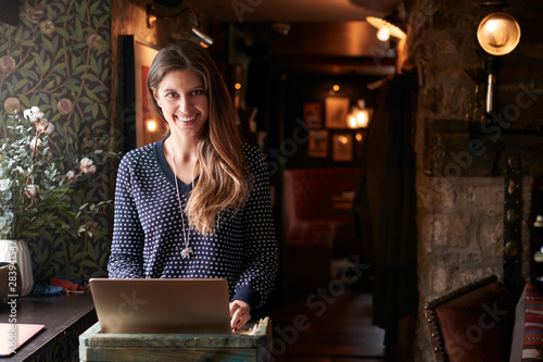 Fotografía Portrait Of Female Receptionist Working On Laptop At Hotel Check In