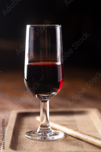 Cuadros en Lienzo Glass of port wine on wooden table and over dark background