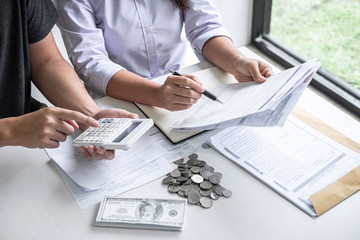 Images of Husband and wife using calculator to calculating expenditure receipt bills of various activity cost and expenses in home office and written make report to plan of spent in future