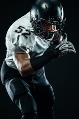 Wall Mural - American football sportsman player in helmet isolated run in action on black background. Sport and motivation wallpaper. Team sports,