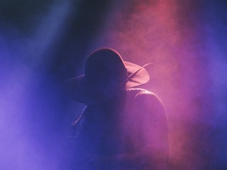 Wall Mural - Musician playing the saxophone at a concert in a club on a dark smokey stage