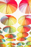 Fototapeta Tęcza - Bright colorful umbrellas umbrellas under the city street  in the sky. Street decoration